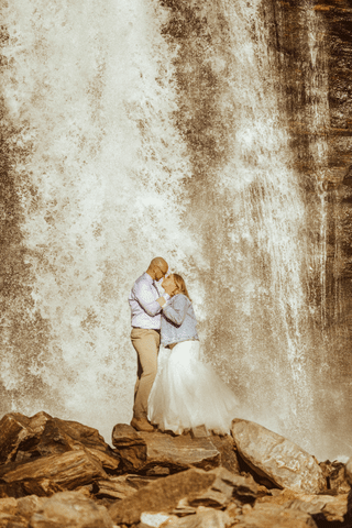 Bride and groom taking pictures in front of a waterfall after North Carolina Elopement